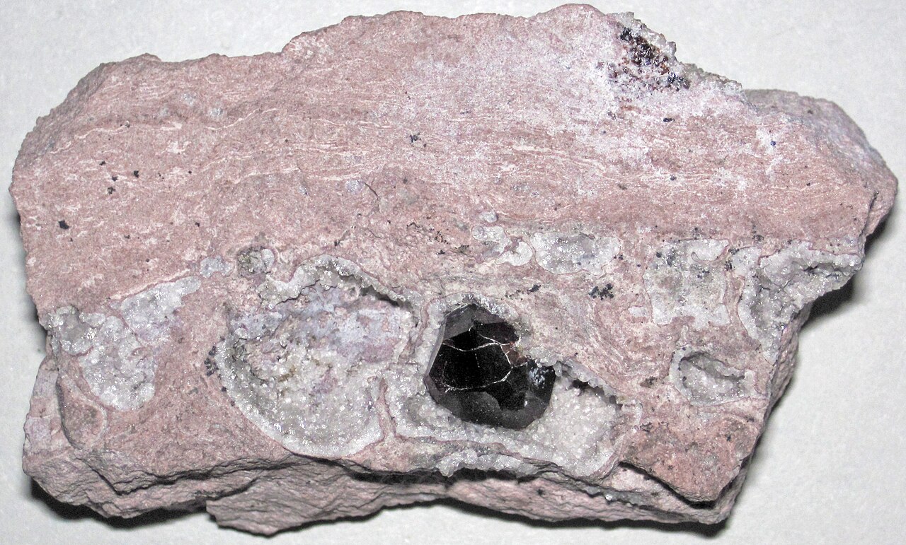 Dark crimson Almandine garnet crystal inside a quartz cavity in Garnet Hill volcanic rock from Ely, White Pine County, Nevada
